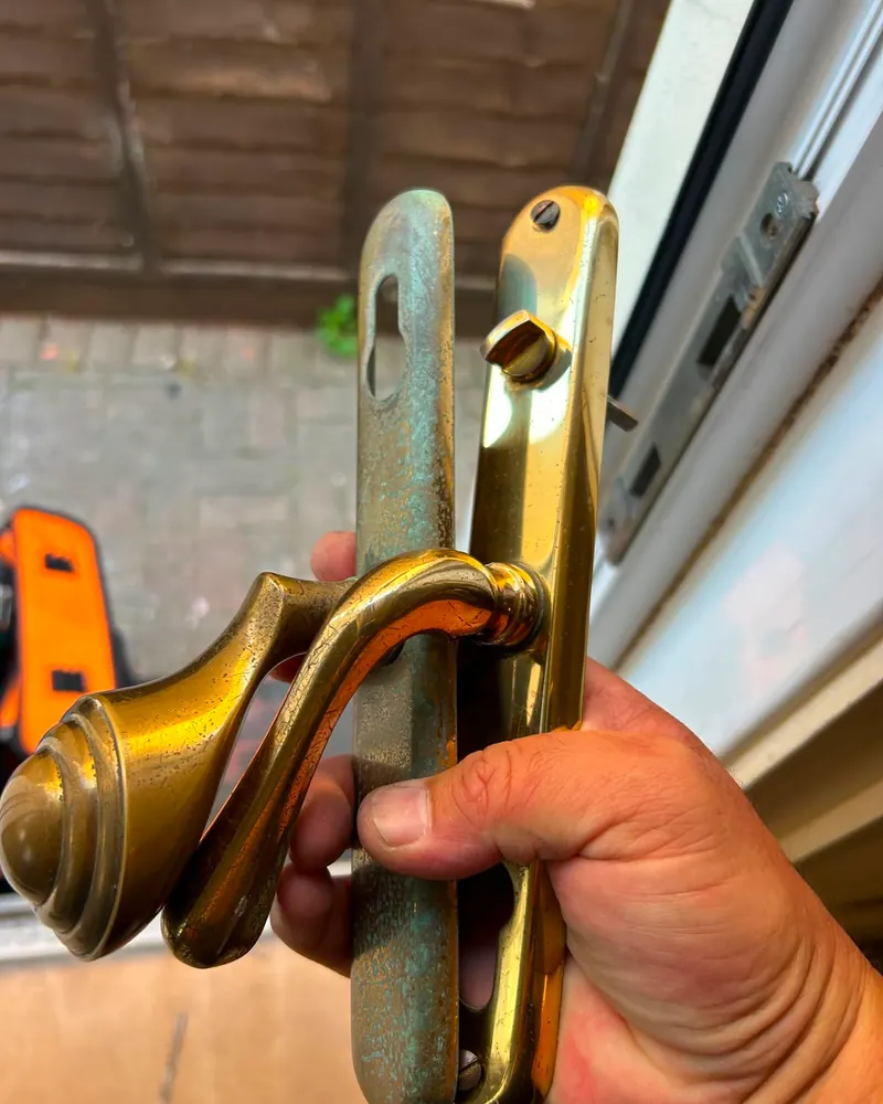 Old worn brass door handle backplates removed from a door